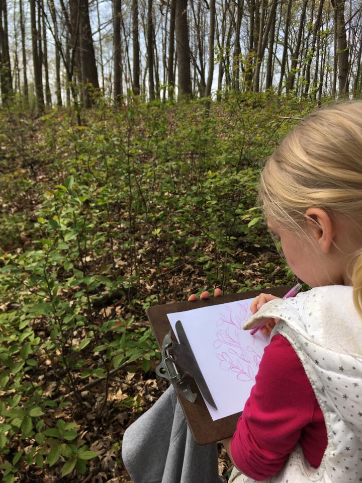 yound student sits in the woods journaling