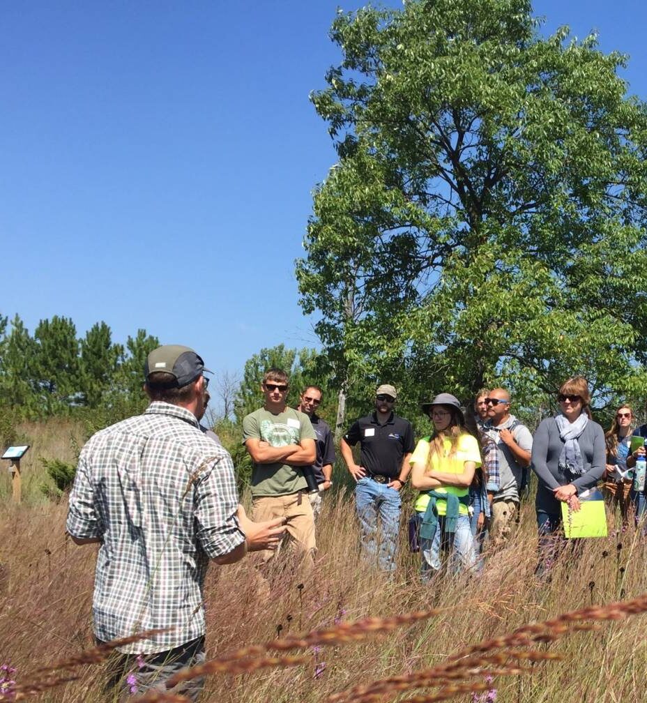 group of adults stands in a prairie for restoration field day