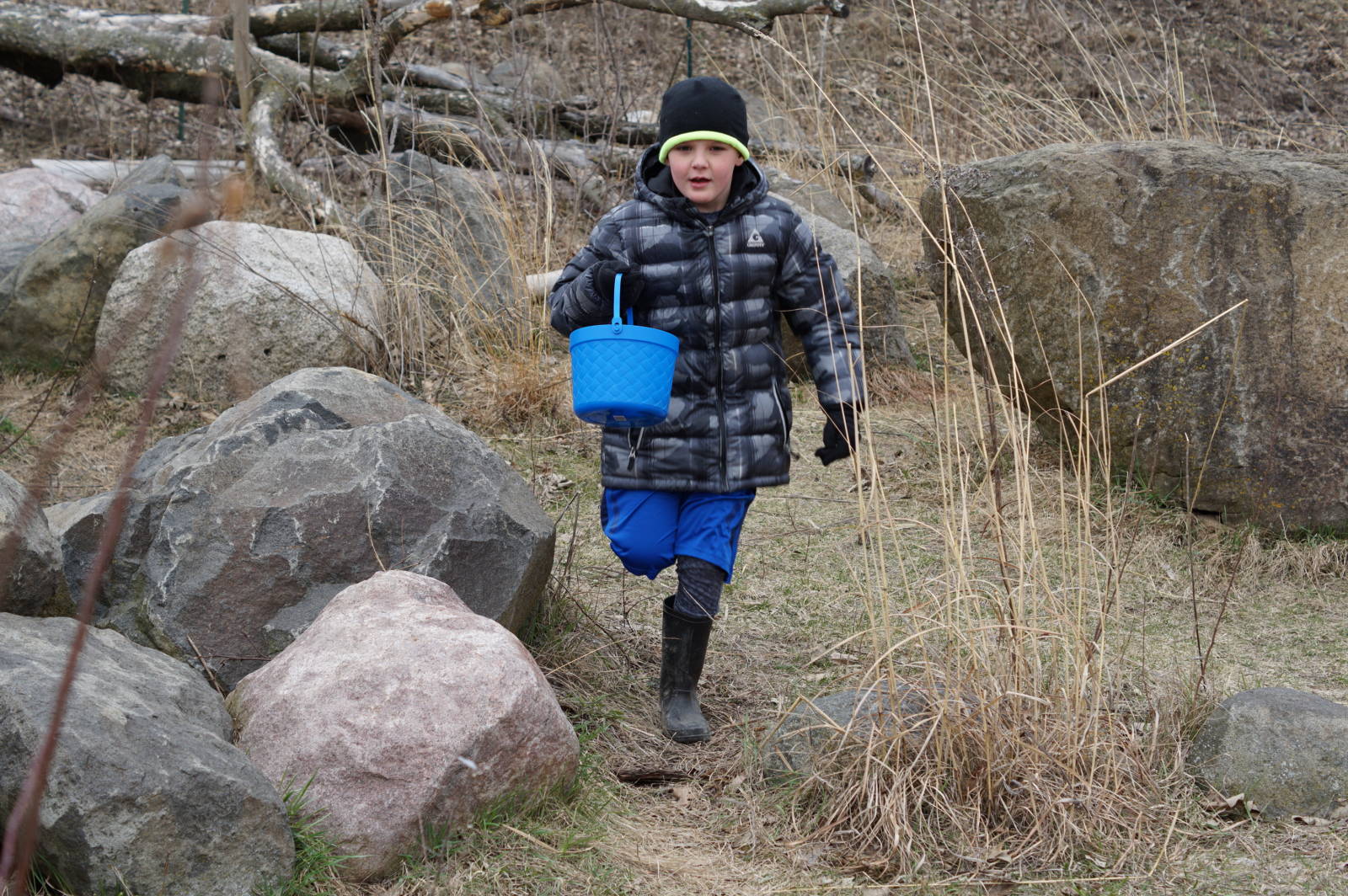 child running with a basket near rocks and prairie grass