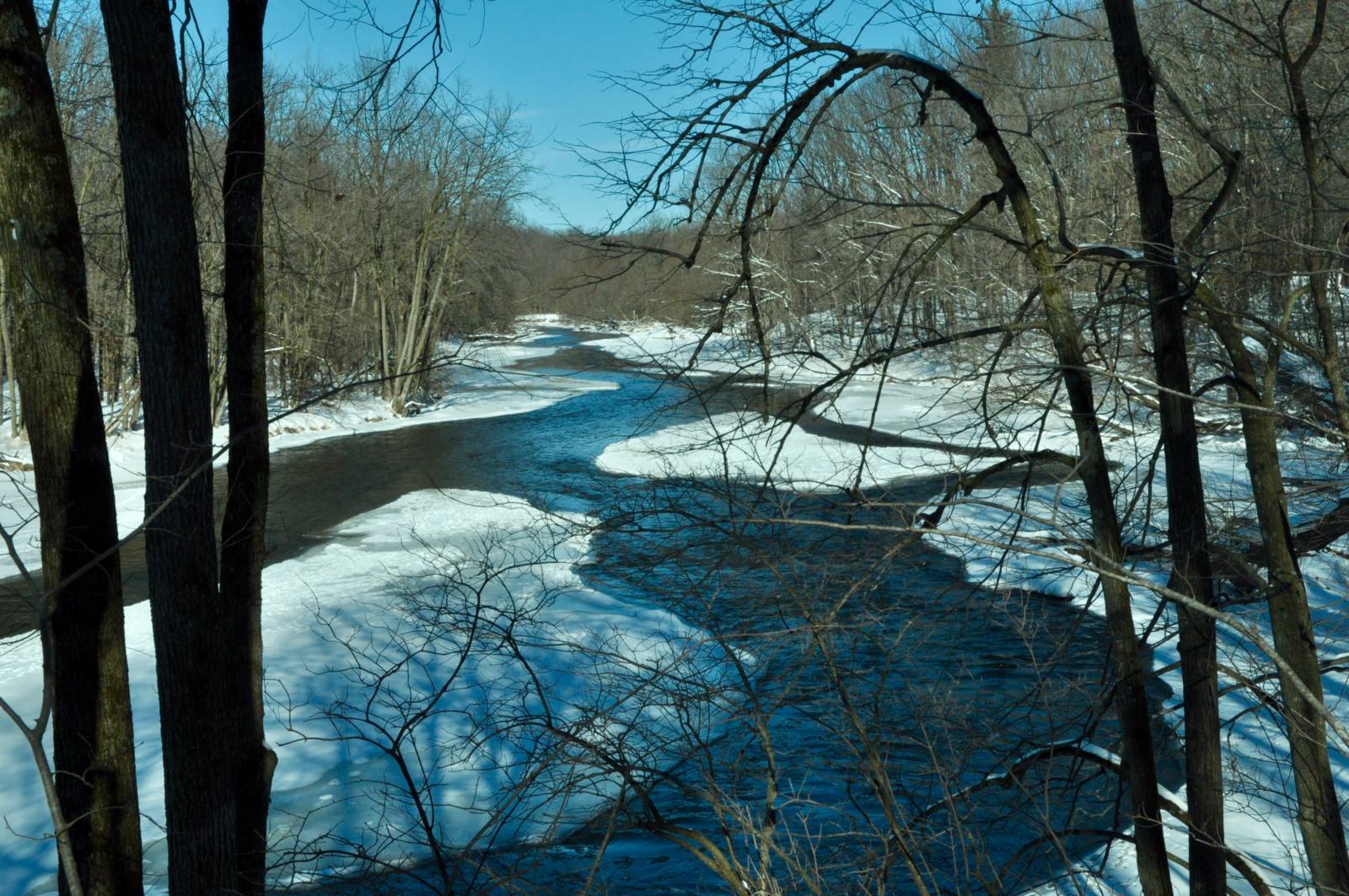 Milwaukee River with snow around it on a sunny day