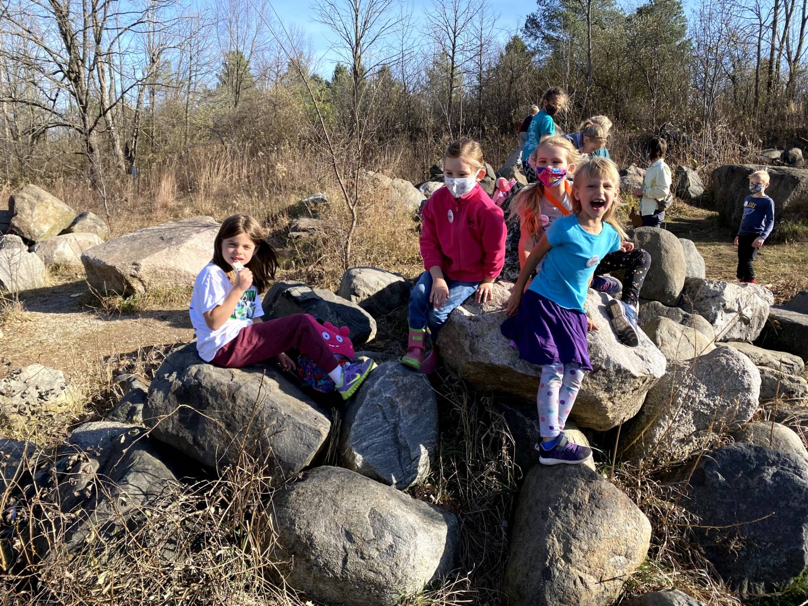 a small group of young kids pose on the Larsen Climbing Rocks on a Fall day