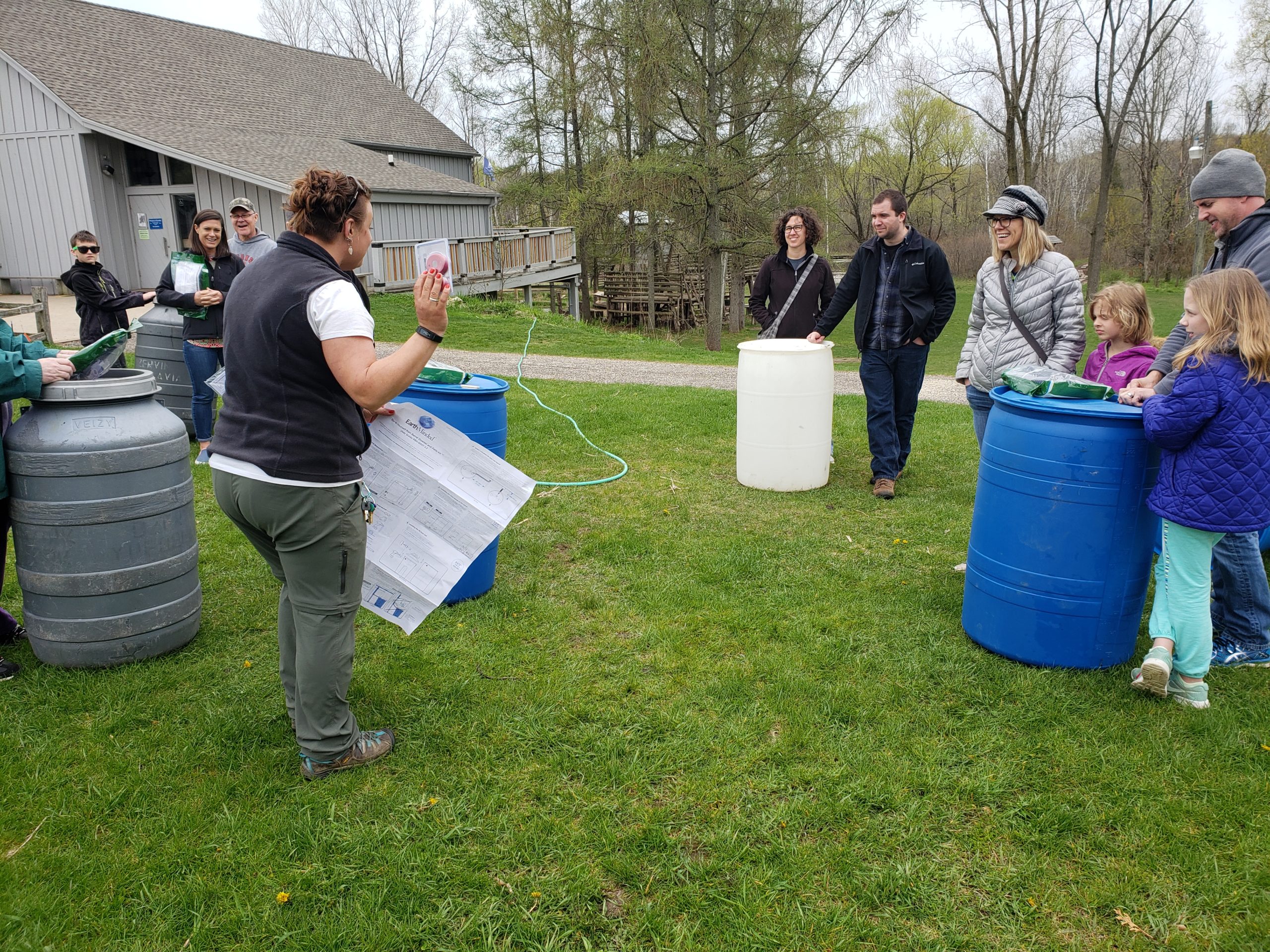 Riveredge educator teaching rain barrel workshop to a group of people outside