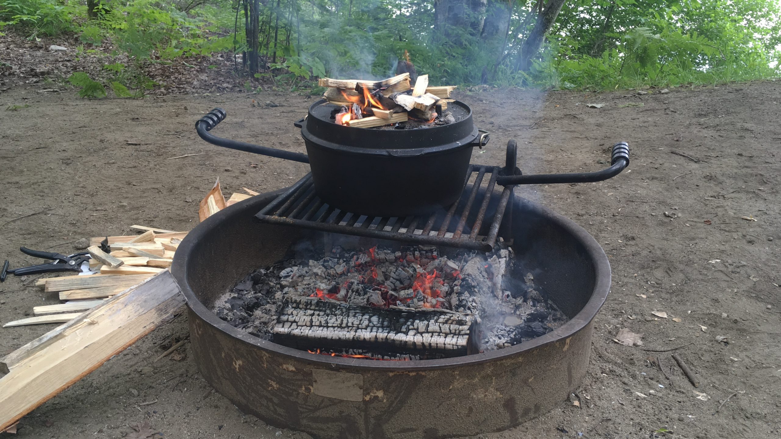 a dutch oven cooking over a lit campfire