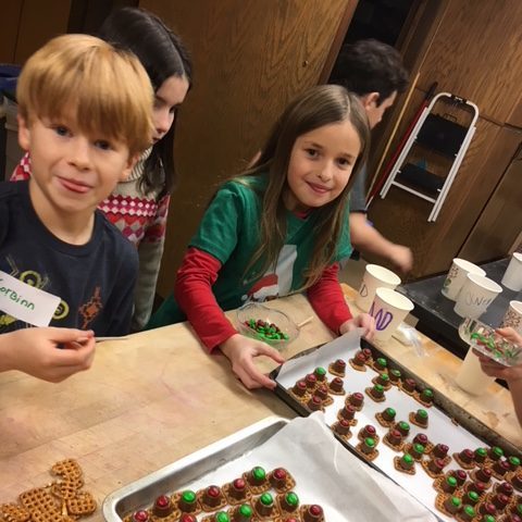 2 kids smiling at the camera showing off their holiday snacks in the Riveredge kitchen