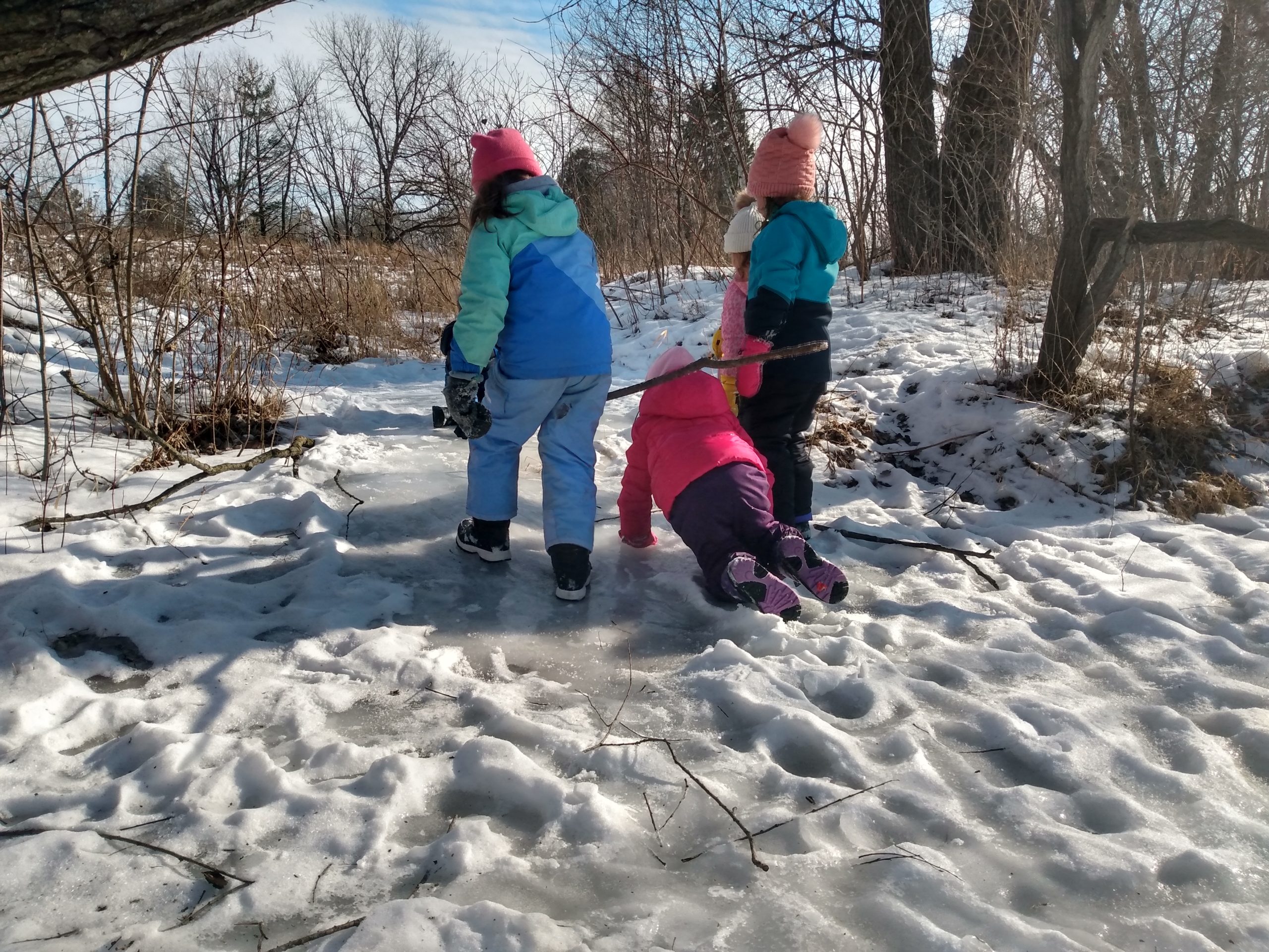 4 young kids walking and crawling on an icy path