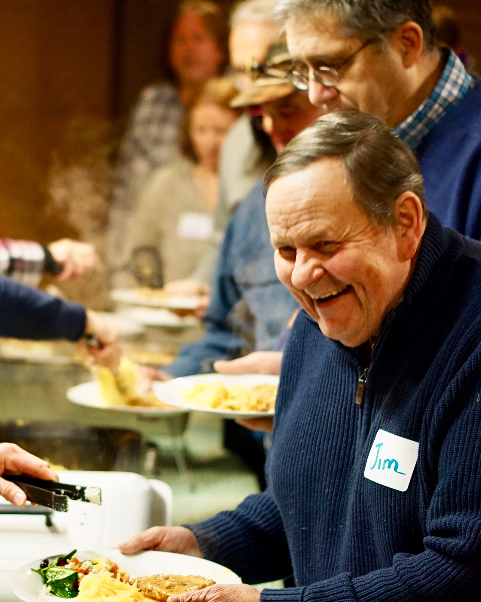 guests being served food by volunteers at the maple syrup supper in the Sugarbush House at Riveredge