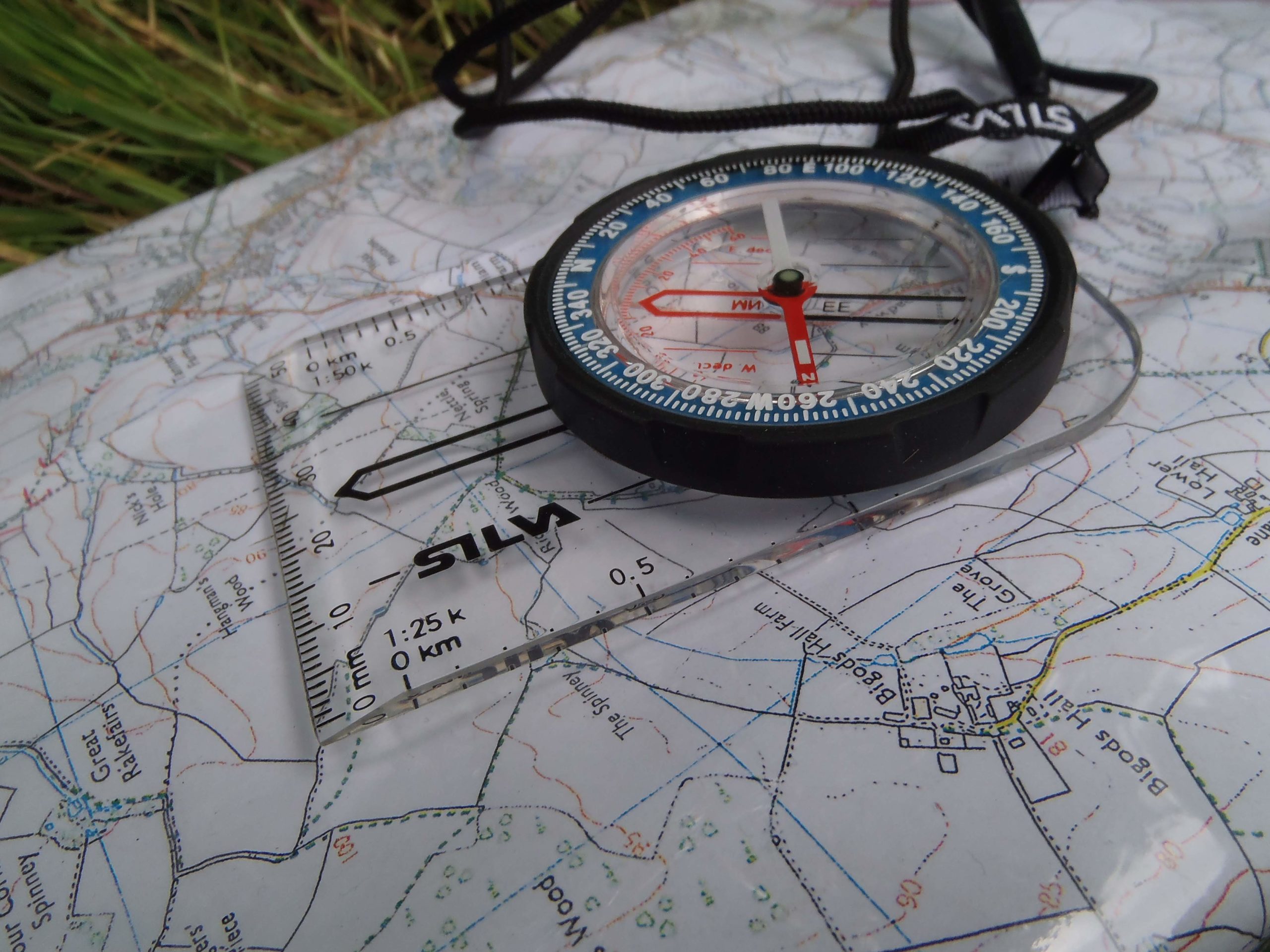 close up of a modern compass on city map in the grass