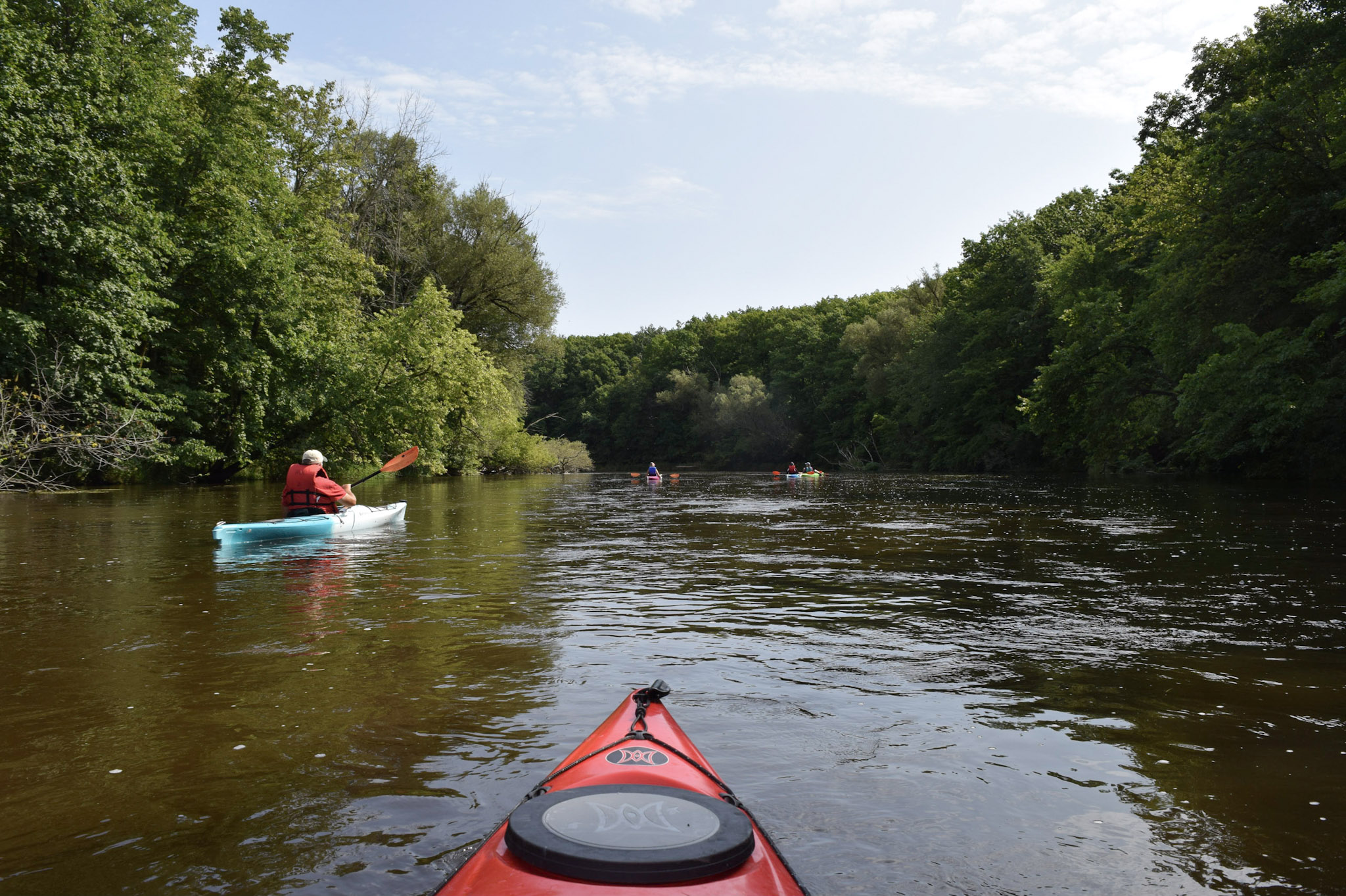 view from a kayak paddling on the Milwaukee River on a sunny summer day with other kayaks in front