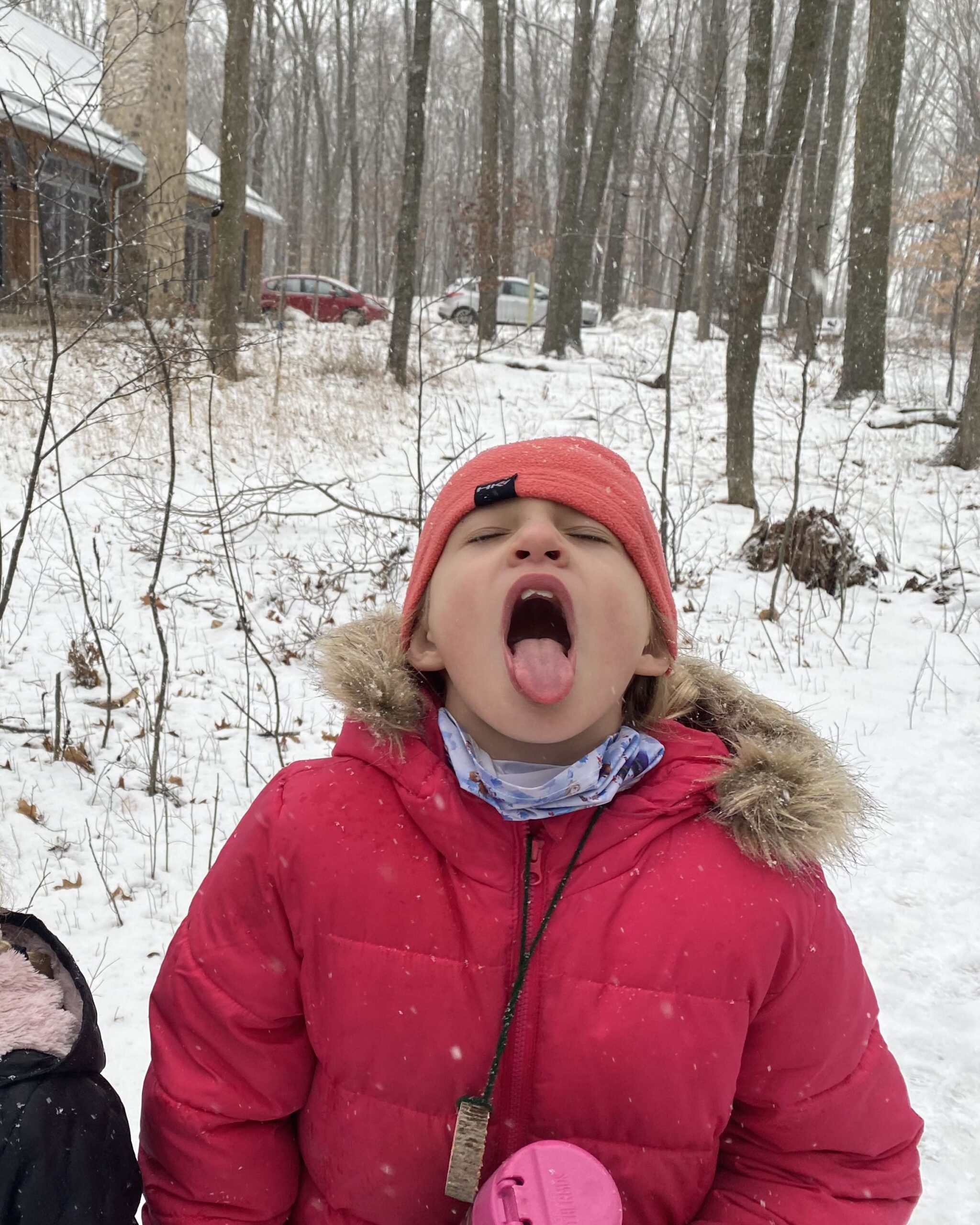 a young girls stands outside the Riveredge Sugarbush House catching snowflakes in her mouth