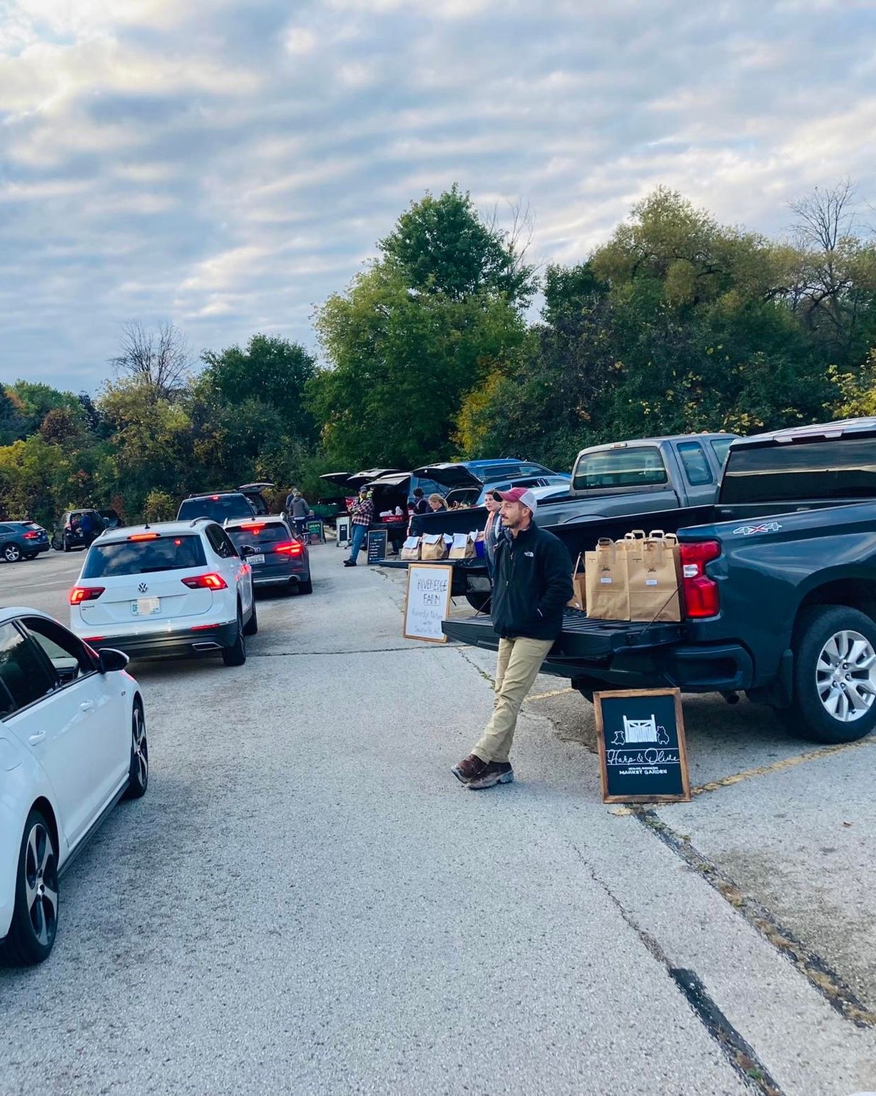 cars are lined up to buy local produce from growers selling itesm from the back of their vehicles