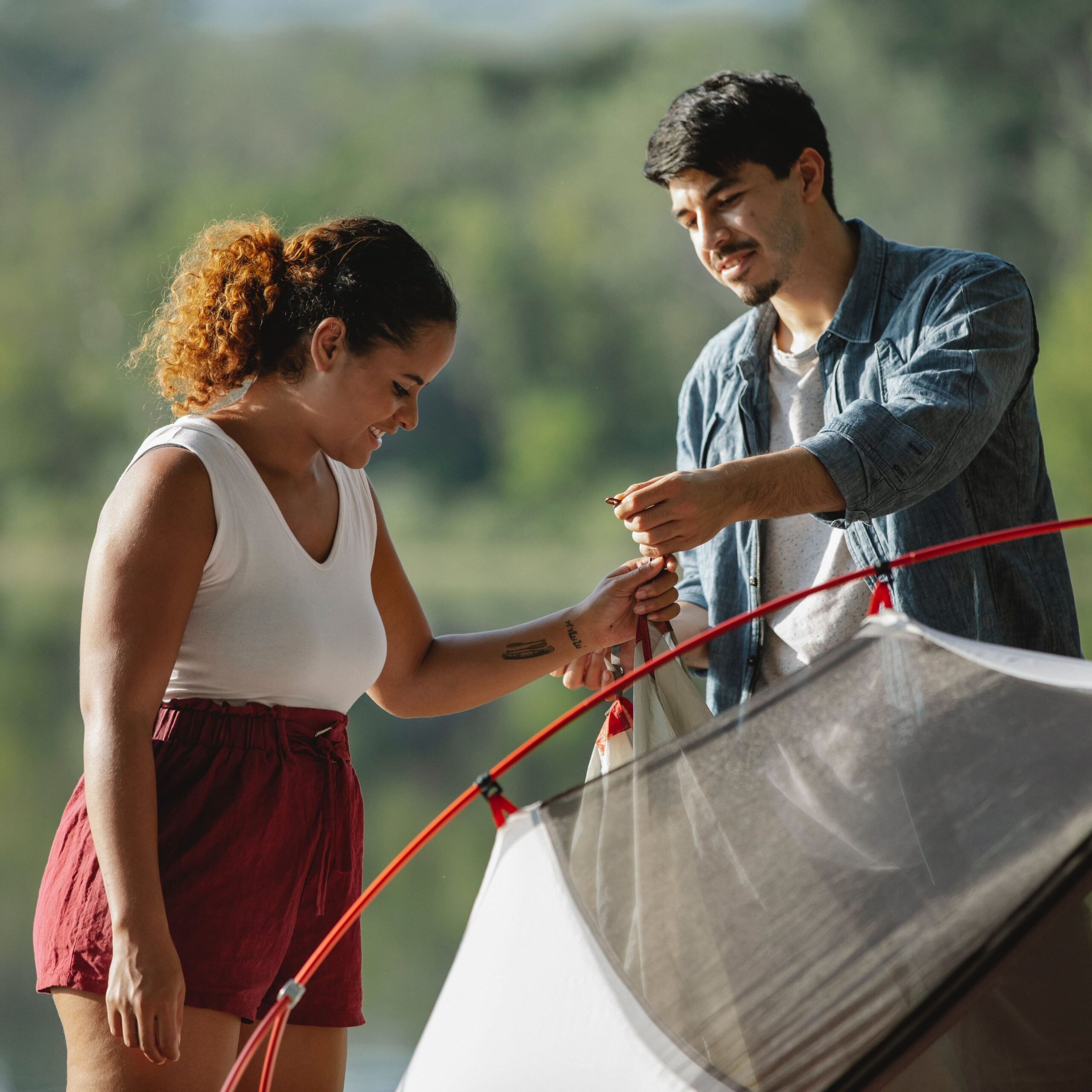 2 people smiling while setting up poles on a tent