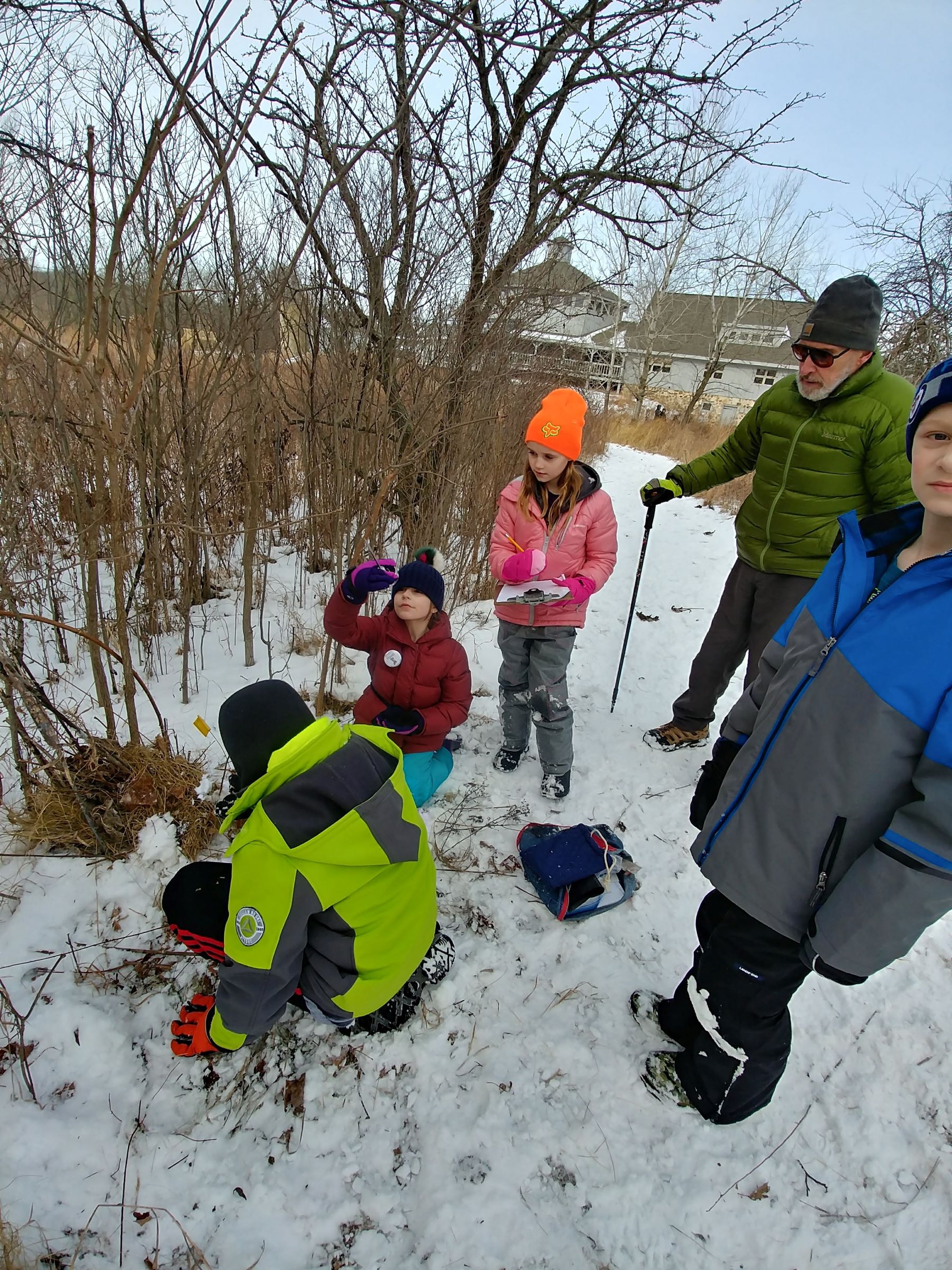 a small group of kids looking at prairie grasses in winter